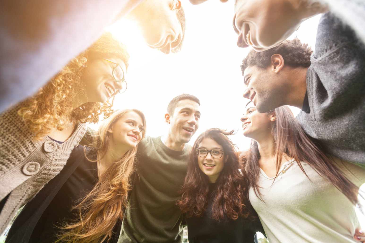 Eine Gruppe von Menschen unterschiedlicher Ethnien steht in einem Kreis zusammen. Alle lachen. Privatdetektive der Kurtz Detektei Stuttgart.